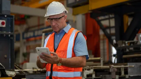 Técnico revisando una orden de trabajo en una tablet dentro de planta