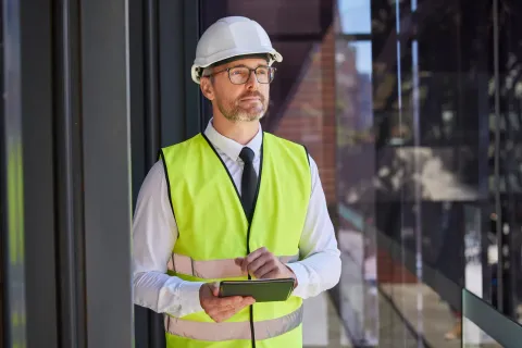 Ingeniero con tablet evaluando la arquitectura tecnológica de un proyecto industrial