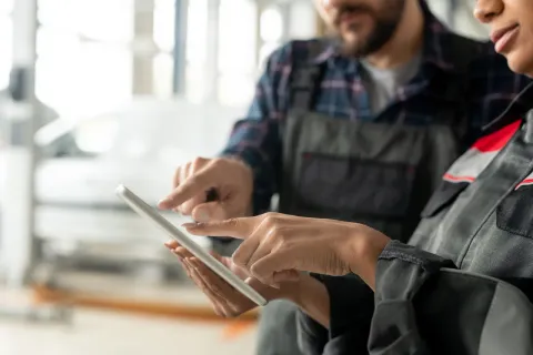 Técnica mostrando en una tablet las funciones de un software CMMS a un colega durante una demo