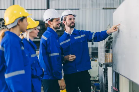 Equipo de mantenimiento planificando el trabajo semanal frente a una pizarra en planta
